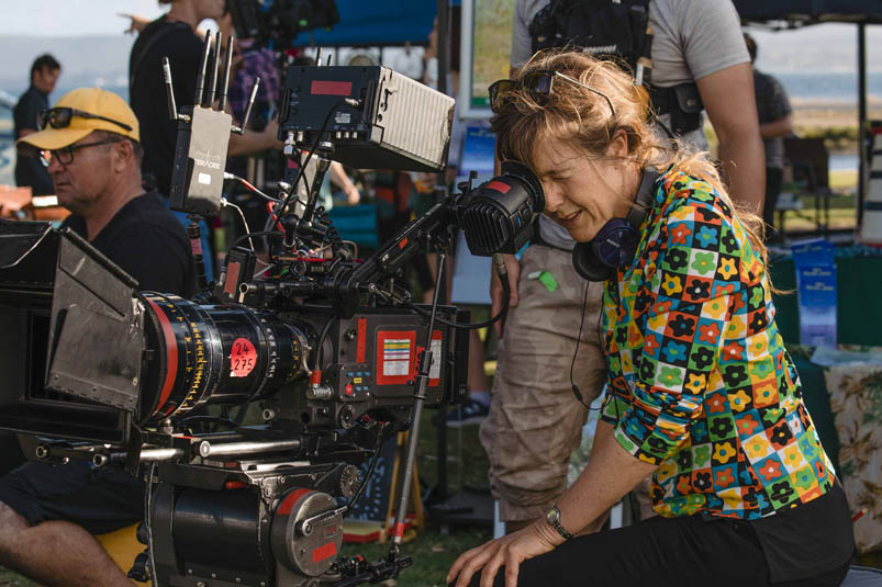 Director Renee Webster on set with a professional film camera.