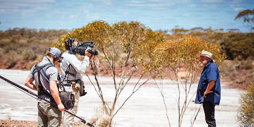 Two crew members with camera and sound equipment filming ‘Dust Devils’ Mike Armstrong in the outback