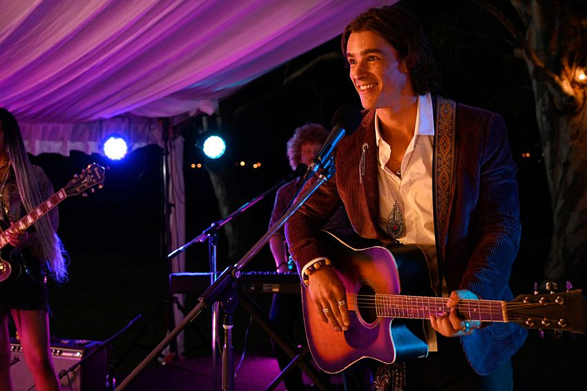 Brenton Thwaites (as Devon) on a stage with a guitar