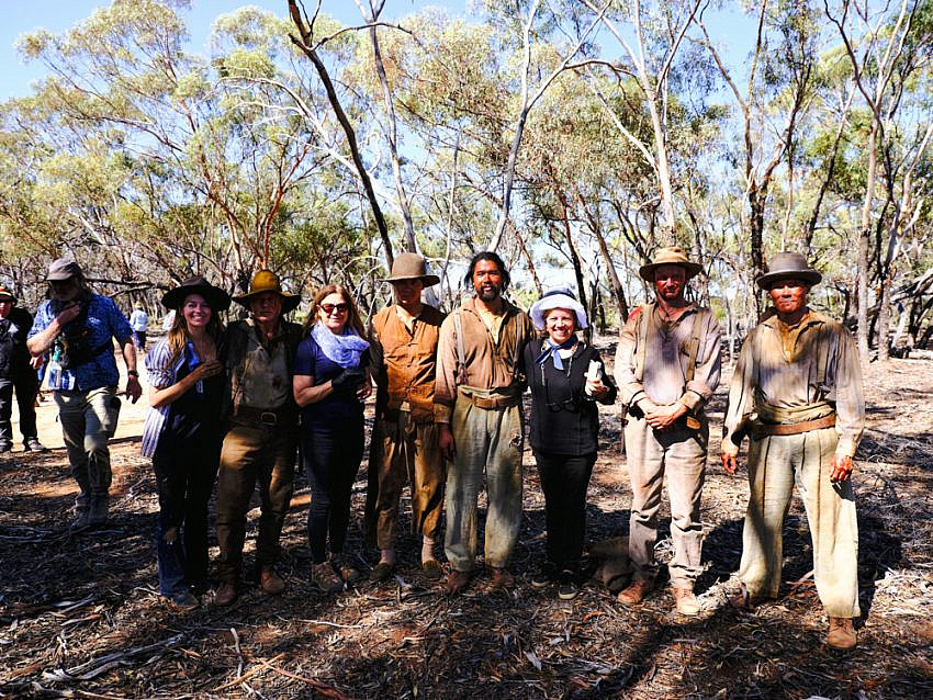 Hair and Makeup department and Extras with special effects makeup behind the scenes in the bush.